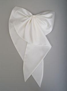 a white bow is hanging on the wall in front of a gray background and it looks like something out of space