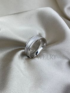 the wedding band is set on top of a white satin fabric, and it looks like it