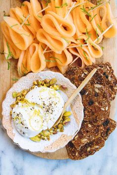 an assortment of food is displayed on a wooden platter, including carrots and crackers