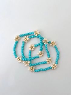 one turquoise seed bead flower bracelet with 14k gold accents made on a durable stretch elastic cord please refer to our sizing guide before you purchase Turquoise Beaded Flower Bracelet, Turquoise Beaded Flower Bracelets, Turquoise Flower Bracelets With Colorful Beads, Handmade Turquoise Flower Beaded Bracelets, Adjustable Turquoise Flower Beaded Bracelet, Seed Bead Flower Bracelet, Bead Flower Bracelet, Seed Bead Flower, Seed Bead Flowers