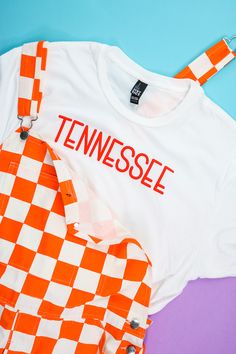 an orange and white checkered shirt with the word tennessee on it next to a pair of scissors