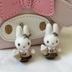 two little bunny figurines sitting next to a pink purse