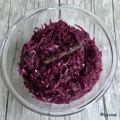 a bowl filled with red cabbage on top of a wooden table