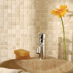 a bathroom sink with soap and a flower in the corner