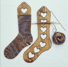 two pairs of socks with hearts cut out of them next to a ball of yarn