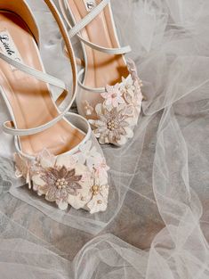 a pair of white shoes with flowers on the toes and heels that are covered in tulle