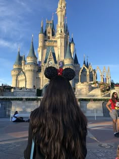 the back of a woman's head in front of a castle at disney world