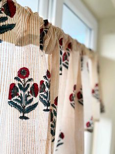 curtains with red flowers are hanging in front of a window