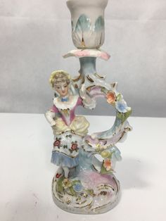 a glass figurine with a woman holding a hat on it's head