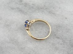 This classic ring is timeless and elegant, a three stone style that has been popular for centuries, and will remain fashionable for years more to come. The beauty of this style of ring is the focus it gives the stones - there's no distracting from their luxurious sparkle! We've set this ring with one of our finest sapphires. Originating in Sri Lanka, we chose this Ceylon Sapphire personally during one of our frequent gem buying trips. The color is perfection, a rich cobalt blue that is considere Classic Formal Sapphire Ring With Trillion Cut, Classic Trillion Cut Sapphire Ring, Classic Trillion Cut Sapphire Jewelry, Luxury Three Stone Sapphire Ring, Yellow Gold Three-stone Sapphire Ring, Classic Trillion Cut Brilliant Sapphire Ring, Classic Sapphire Ring With Trillion Brilliant Cut, Yellow Gold Three Stone Sapphire Ring, Classic Yellow Gold Trillion Cut Rings