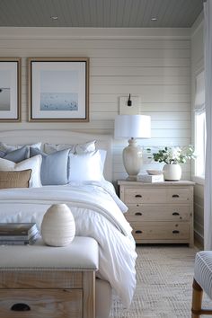 a bedroom with white bedding and two pictures on the wall