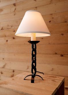 a lamp sitting on top of a wooden table next to a wood paneled wall