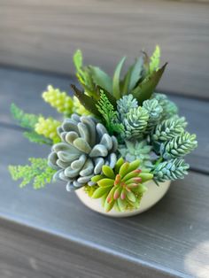 an arrangement of succulents in a small white bowl