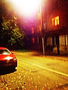 a red car is parked on the street at night