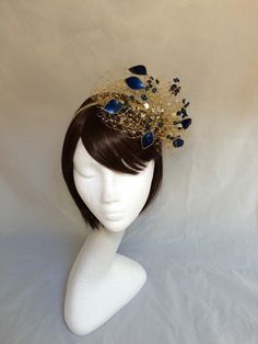 Delicate gold and navy veiled fascinator perfect for the guest who wants something fairly understated. This design is a beautiful selection of navy blue glass effect leaves clustered together amongst a fine layer of veiling and set onto a fine comfort base tiara band. As with all our designs, this piece can be made exact to the image or in any colour combination to match in with your outfit. If a specific colour is required customers can message over an image of their outfit and accessories, or Gold Teardrop Crown Headband For Parties, Royal Tall Crown For Wedding, Gold Headpiece With Round Crown For Party, Gold Round Crown Headpiece For Party, Elegant Gold Teardrop Crown Headband, Gold Headband Fascinator For Party, Gold Headpieces For Royal Ascot Formal Occasion, Gold Costume Hats With Structured Crown For Evening, Gold Round Crown Headpiece For Weddings