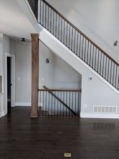 an empty living room with stairs and hard wood flooring