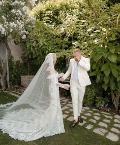 a bride and groom walking through the grass