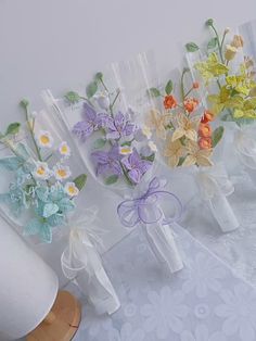 four vases with flowers in them sitting on a table next to some paper bags