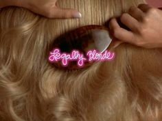 a close up of a woman cutting her hair with a comb and scissors in front of her