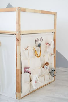 a toy storage unit with stuffed animals on the bottom shelf and personalized wall hangings