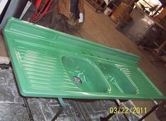 a green sink sitting on top of a metal table next to a man in a red shirt