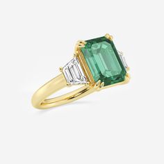 an emerald and diamond ring with two baguets in yellow gold plated silver