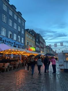 people are walking down the street with umbrellas over their heads and food stalls on either side