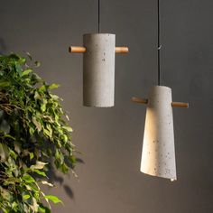 three concrete lamps hanging from the ceiling next to a potted plant