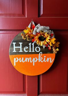 a hello pumpkin sign hanging on a red door