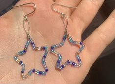 a pair of blue and white beaded star earrings on a person's hand