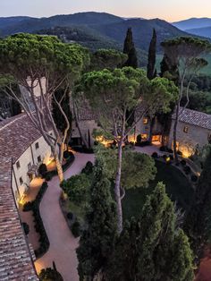 an aerial view of a house with trees and mountains in the background at night time