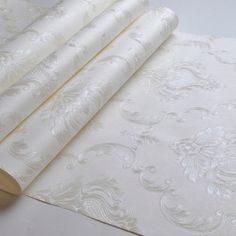 three rolls of white wallpaper sitting next to each other on top of a table