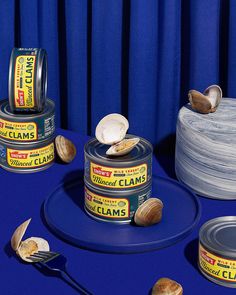 three tins of clams are sitting on a blue surface