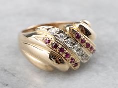 This vintage cocktail band is set with sparkling rubies in sweeping polished gold. Centered with a single row of high-quality diamonds which complement the magenta gemstones beautifully, and help form the domed design of the ring that makes this piece so eye-catching! Metal: 14K Yellow and White Gold Gem: 7 Diamonds totaling .17 Carats, G in Color, SI1 in Clarity Gem Measurements: 1.5 mm, Round Accents: 12 Rubies Ring Size: 7.25 Marks: "-(B)-14K" Stamped on the inside band Yellow Gold Sapphire Ring, Antique Diamond Engagement Rings, Retro Cocktail, Estate Ring, Statement Rings Diamond, Antique Wedding Rings, Estate Rings, Bridal Wedding Rings, Vintage Cocktail