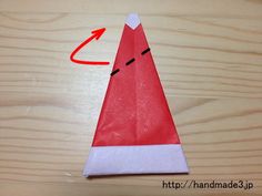 an origami paper cone with a red arrow pointing to the left on a wooden surface