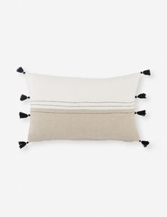 a white pillow with black tassels on it