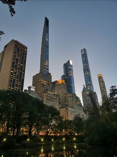 the city skyline is lit up at night, with skyscrapers in the foreground