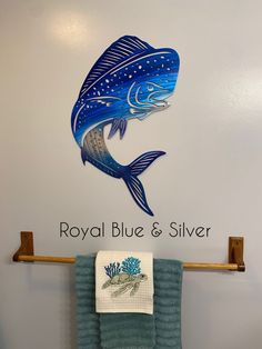 a towel hanging on a rack in front of a wall with a fish and words royal blue & silver