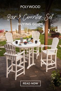 a white table and chairs sitting on top of a brick patio next to the water