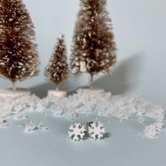 two small trees are in the snow with tiny snowflakes on them, and one is standing out from the others