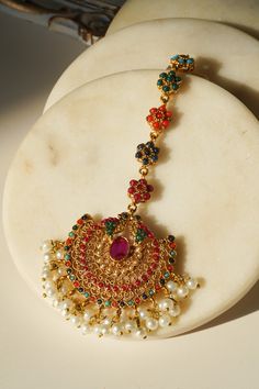 Introducing the Imaari Statement Necklace Set with Maang Tikka and Chandbali Earrings. This exquisite necklace set features multicolor navratan stones with elegant gold plating and high-quality brass filling. The set includes a stunning maang tikka and matching chandbali earrings, making it a perfect style statement for special occasions or parties. The Imaari necklace set is designed to blend tradition with elegance. The intricate design of the maang tikka and the dazzling chandbali earrings co Temple Jewelry Style Tikka For Eid Celebration, Temple Jewelry Tikka For Eid Celebration, Eid Celebration Temple Jewelry Tikka, Festive Multicolor 22k Gold Bridal Necklace, Festive Multicolor Chandbalis With Intricate Design, Festival Gold Plated Temple Jewelry Tikka, Temple Jewelry Style Multicolor Chandbalis For Festive Occasions, Multicolor Earrings For Diwali Rituals, Temple Style Gold Plated Tikka For Festivals