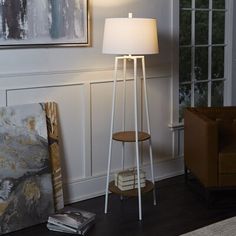 a floor lamp with a white shade on it in a living room next to a couch