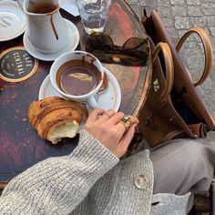 a person is sitting at a table with coffee and croissants on it