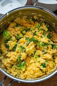 broccoli and rice in a silver pot on a wooden table with utensils