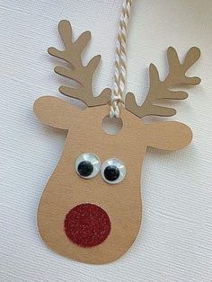 a paper reindeer ornament hanging from a string on a white wall with red nose and antlers