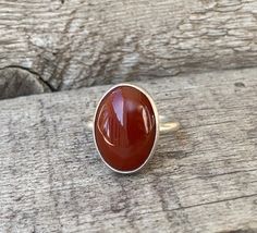 A rich dark blood red orange carnelian has been set in sterling silver with a handmade ring band from sterling silver half dome wire. This stone has inner crystals of differing color that show throughout-it is not a solid blood red orange. The stone has been set vertically (north to south) and is 13mm x 18mm in size and about 5-6mm in height. It is also available in a horizontal (east to west) setting. Made to order! Chose your size and setting direction at checkout! Carnelian brings out hidden Red Carnelian Oval Cabochon Ruby Ring, Red Crystal Ring, Orange Carnelian, Dark Blood, Carnelian Ring, Blood Red, Red Crystals, Crystal Ring, Asheville Nc