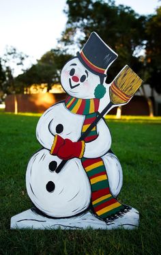 a snowman with a hat and scarf holding a paintbrush sitting on top of it's head