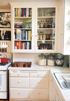 a kitchen with white cabinets and shelves filled with books