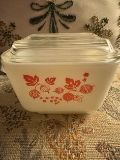 a white glass dish with red designs on the front and bottom sitting on a table