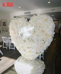 there is a heart made out of flowers in the middle of a room with white chairs